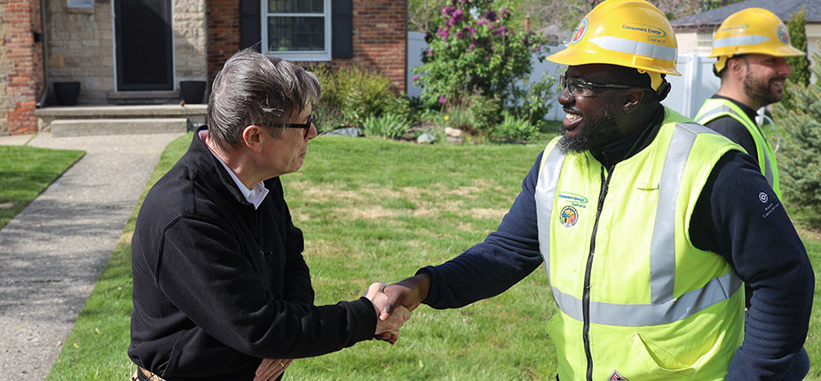 Consumers Energy natural gas worker speaking to a woman in front of her homw
